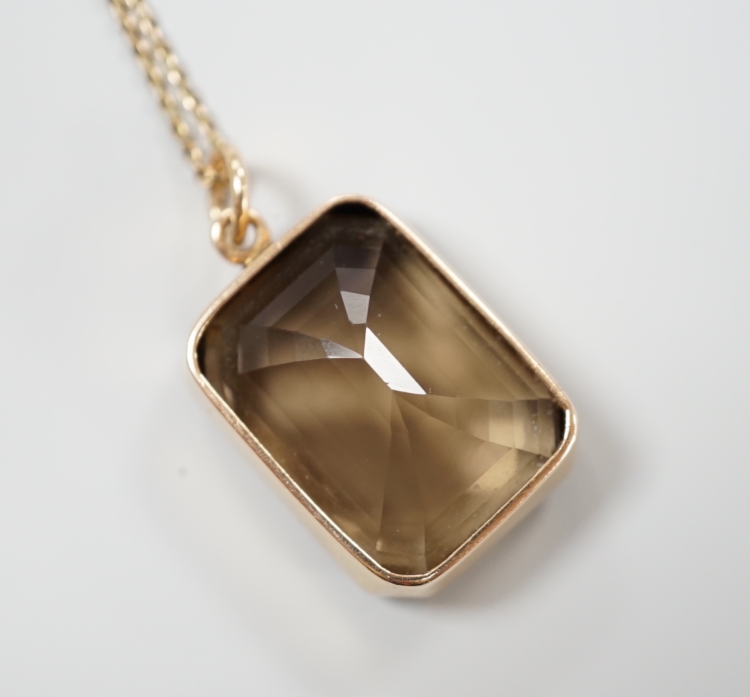 A yellow metal mounted smoky quartz pendant, 24mm, on a yellow metal fine link chain(a.f.), gross weight 15.6 grams.